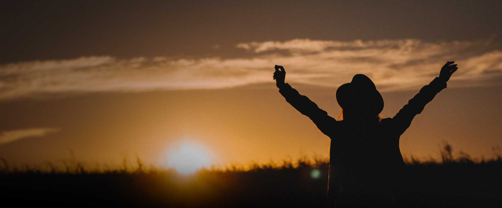 Sun rising in front of shadow of person reaching up